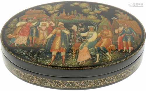 An oval Russian lacquer box with depiction of a woman with a spinning wheel in a garden.