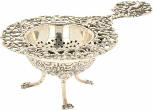 Silver tea strainer with stand.