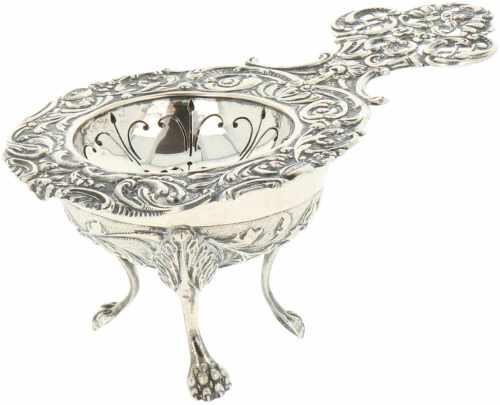 Silver tea strainer with stand.