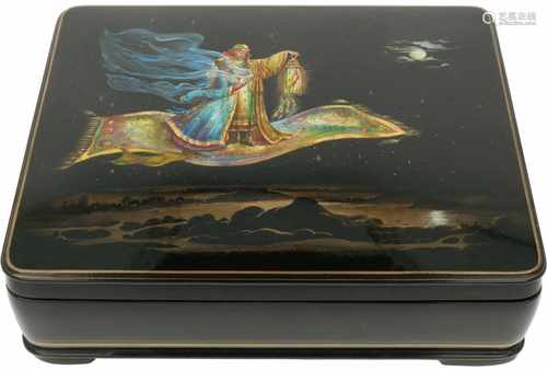 A Russian lacquer box with depiction of two figures and a bird on a flying rug.