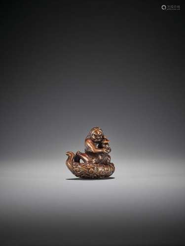 A POWERFUL WOOD NETSUKE OF AN ONI ATOP A CLOUD WIT…