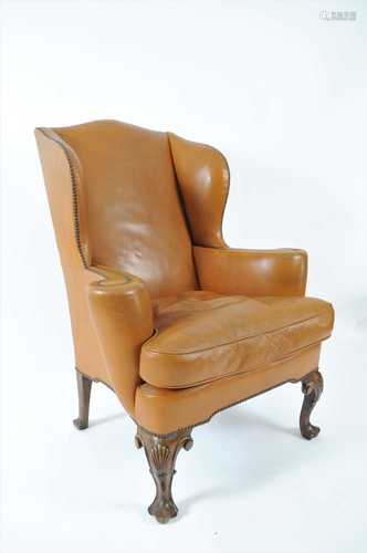 A tan faux leather upholstered wing back armchair