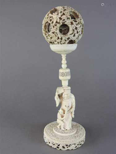 A large Canton carved ivory puzzle ball on figural stand, Qing dynasty, late 19th century, the