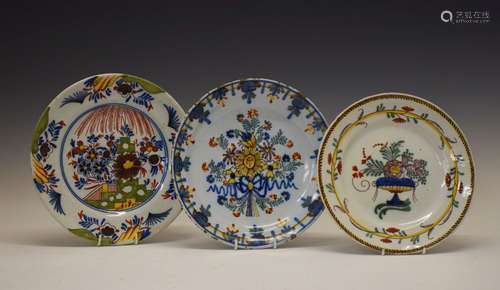 Three 19th Century tin-glazed earthenware plates, each with polychrome floral decoration, largest