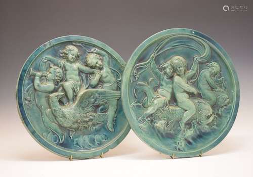 Pair of late 19th Century green-glazed majolica plaques, each of circular form with cavorting