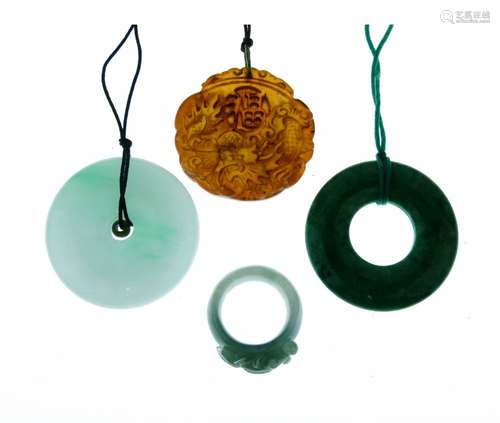 Circular jade pendant, on cord; another similar; a jade ring carved with a fish; and a brown jade