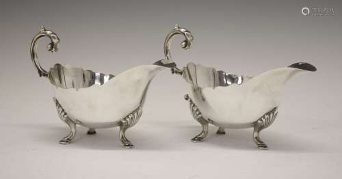Pair of George V silver sauce boats, with shaped rim and standing on tripod hooved feet, sponsors
