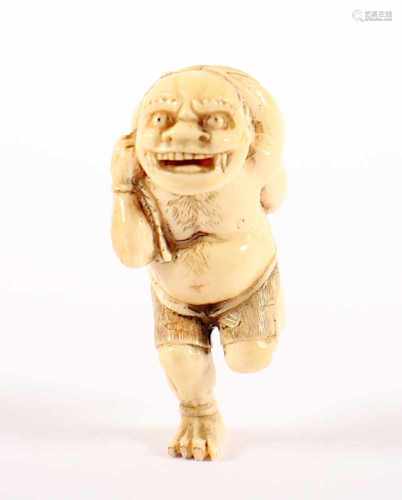 NETSUKE ONI EIN MOKUGYO TRAGEND, Elfenbein, rennend und mit geöffnetem Mund trägt der Oni einen