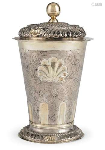 Baroque lidded cup. Silesia, c. 1720. H. 22 cm. Silver, chased, engraved and partly gilded. Stand and lid rim with tongue decoration under pearl band and three shell motifs each. The wall, engraved with rich floral decoration, picks up the theme of tongues and shells. Screwed lid knob added. Minor dent, rest. On the ground MZ: 