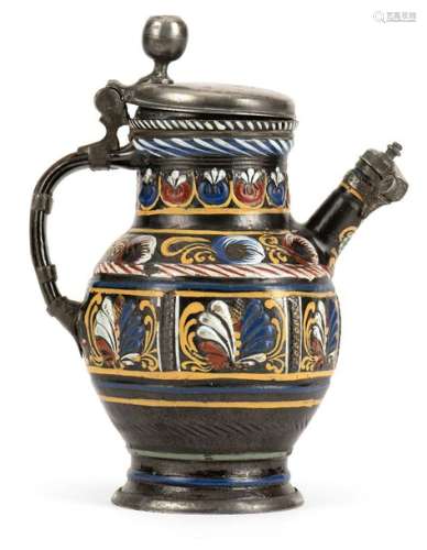 Spout jug. Dippoldiswalde, c. 1690. H. 25 cm. Black-brown stoneware, dark brown engobe, six-sided, palm leaf decoration on the neck, six fields with chain links and palm leaves in the fields, painted in white, yellow, red and blue. Pewter mounting, lid marked Naumburg, Meister Hans Schlüffel, quality brand. Rest., Ages. Provenance: From old South German private property. On the form see Horschik, p. 252, no. 147.