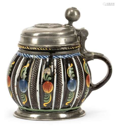 Melon jug. Dippoldiswalde, circa 1680. H. 16 cm. Black-brown stoneware, engobed and painted in green, yellow, red, white and blue. Alternating vertical stripes with scale pattern and pomegranates. Tin mounting, plaque embedded in the lid. Jumps, best. Provenance: From old South German private property.