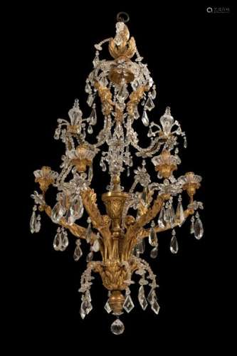 Transition chandeliers. Italy, probably Genoa, second half of the 18th century. H. 130 cm. Six-flame. Iron frame with carved and gilded applications, rich cut glass decoration. Rest. Erg. agessp. retrospectively electrif. Impressive ceiling chandelier with leaf tendril decoration and mascarons, in very attractive condition.