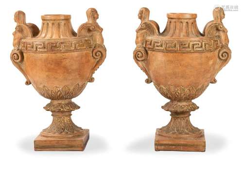 Pair of terracotta vases. Classicist style. H. 80 cm. Urn-like vases with sphinx handles, meandering frieze and leaf decoration. Partly gold-plated. Age and usessp.