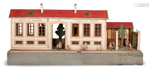 Model of a school as an automaton. France, c 1920. 70x158x60 cm. Plywood and others, painted. The machine moves children's dolls along a predetermined path from the playground to the primary school, which is divided according to the labelling for boys and girls. The classrooms are equipped with small benches. There are a total of 17 dolls on the tape. Electrif. Age and usage test function not checked.