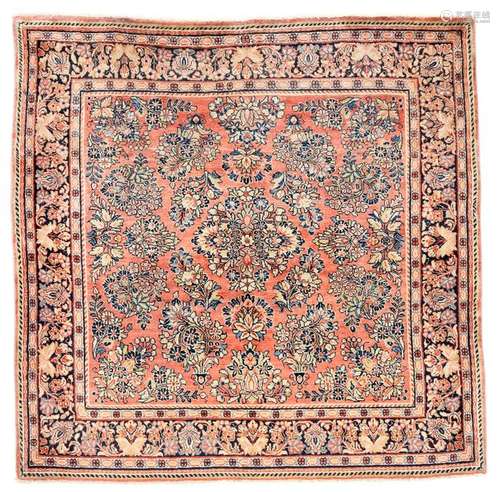 Magnificent Saruk. Western Persia, circa 1940. 149 by 152 cm. Fine perennial flower motifs and stylised flower tendrils cover the salmon-coloured background with a loose scattering and flank a discreetly restrained floral medallion. A floral vine border of adjusted palmette blossoms frames the squarely proportioned pile-work. Well preserved.