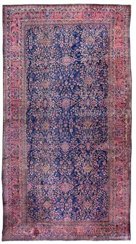 Impressive Sarouk palace carpet. Western Persia, circa 1920. 692 x 385 cm. A fine blue-ground saruk with a generous and elegantly designed pattern repeat of arabesquely curved palmette vines. The course of the pattern is rhythmicized in the vertical axis by two geometric-rhomboid forms in alternating arrangement: Small rhombic medallions in the middle of flowering perennials on the one hand alternate with rhombic motifs formed from climbing plants on the other. Oval flower medallions are set into the large paradisiacal garden field on the central axis. Due to the light pastel colouring of the tendrils and blossoms on a blue background, this high-quality commissioned work achieves a high aesthetic standard. Masterful knotting. Provenance: North German private property. - Min. knotted. Insg. very well preserved.