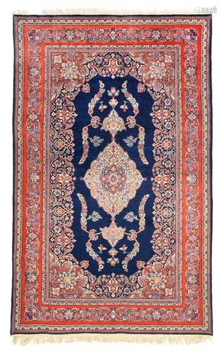 Keshan. Central Persia, circa 1940. 211 x 128 cm. A keschan of good wool quality with a dark blue, plain field and central medallion. The design of the red-ground main border is striking here, with a narrow palmette vine that does not completely fill the width of the border. Classic colour palette of red and blue with cream accents. Original woven finish preserved at the bottom end. Selective repilling. Apart from that, the building is in very good overall condition.