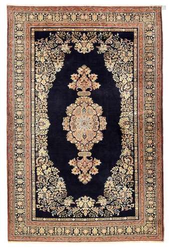 Fine silk ghom. Central Persia, second half of the 20th century. 214 x 143 cm. Gracile floral ornamentation in a light colour contrasts effectively with the dark blue ground field. The fine knotting is completed by a magnificent floral border. Well preserved.