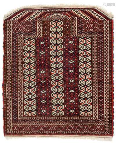 Yomut salachak. Turkmenistan, circa 1900. 115 x 103 cm. A pile-woven saddle cloth with a stepped gable and a field design of vertical pattern stripes inspired by Yomut flatweaves. Filigree border decoration made of geometric structures. Remarkable are the white-ground gable crowning in the style of a cut Göl cartridge on the one hand and the polychrome Schirasi on the other. 