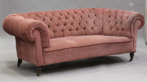 A late Victorian buttoned back Chesterfield settee, upholstered in pink velour, on turned legs,