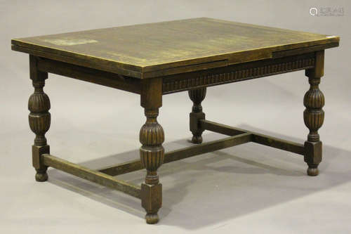 A George V oak drawleaf dining table with reeded baluster and block legs united by an 'H' stretcher,