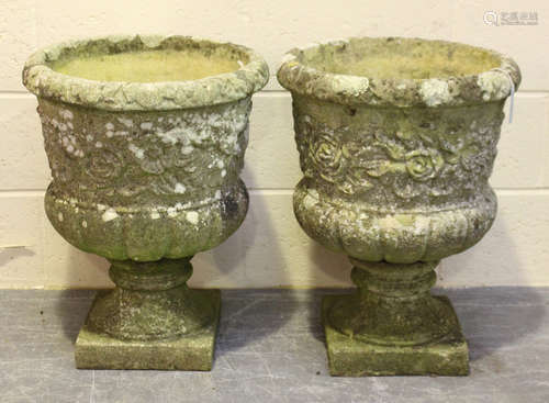 A pair of 20th century cast composition stone garden urns, the half-reeded bodies with flowerhead