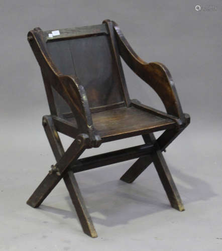 An early 20th century oak Glastonbury chair, the solid seat and back raised on 'X' frame supports,