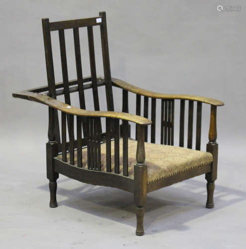 An early 20th century oak reclining armchair, in the manner of William Morris, raised on turned