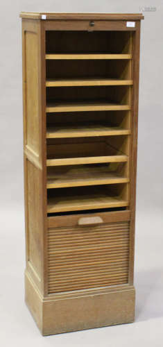 A mid-20th century oak tambour-fronted filing cabinet with sliding shelves, raised on a plinth base,