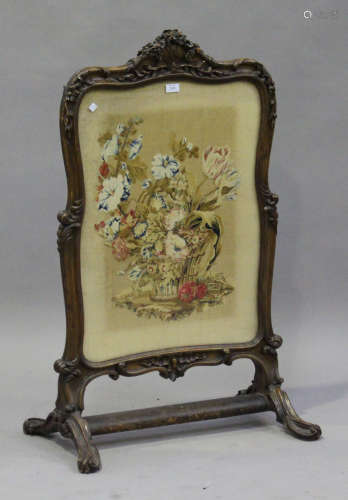 A Victorian carved walnut framed firescreen, inset with a needlework panel, on scroll feet, height