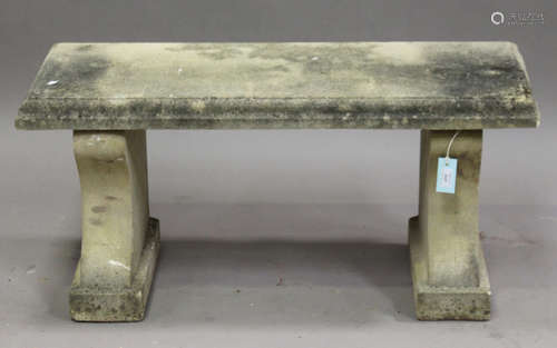 A 20th century cast composition stone garden bench, the rectangular top on a pair of shaped