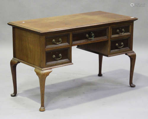 An early 20th century walnut kneehole writing table, the moulded top above five drawers, raised on