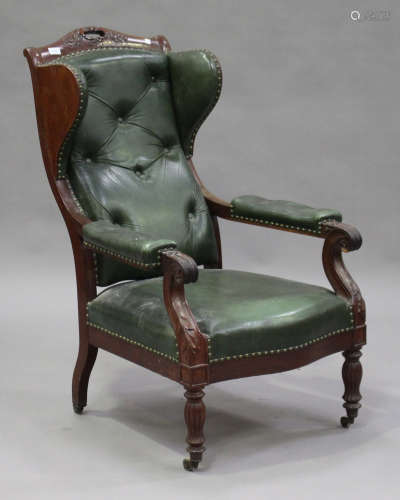 A 19th century French mahogany and buttoned green leather wing back armchair with carved foliate