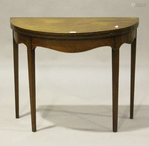 A George III mahogany demi-lune fold-over card table with chequer stringing, on square tapering