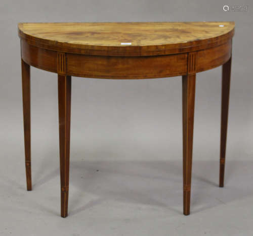 A George III figured mahogany demi-lune fold-over card table with crossbanded and inlaid decoration,