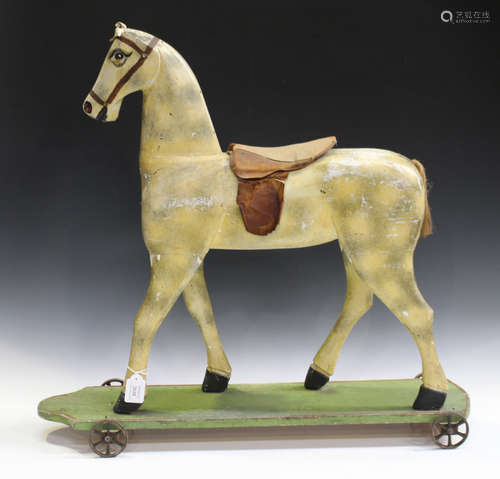 An early 20th century carved and painted wooden primitive push-along model of a horse, the plank