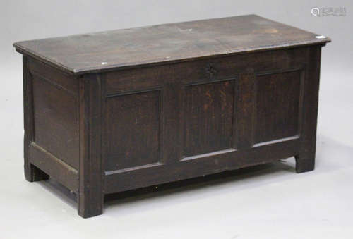 An 18th century oak coffer, the hinged lid revealing a candle box above a triple panel front, on