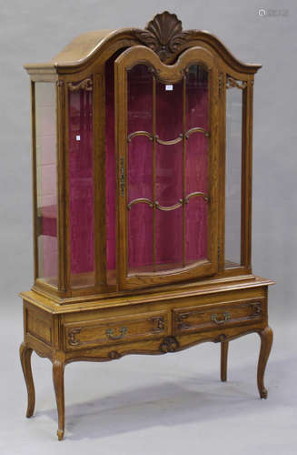 A 20th century French oak vitrine with carved scroll decoration, the arched top fitted with a single