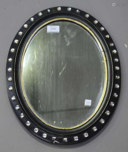 A 19th century Irish ebonized oval wall mirror, the frame inset with glass squares, 46cm x 35cm.