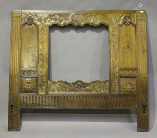 A 19th century French walnut headboard with central aperture, carved with overall leaf decoration