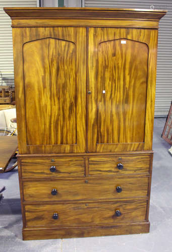 An early Victorian figured mahogany linen press, the angular pediment above a pair of arched panel