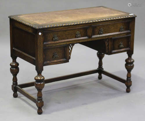 A George V oak kneehole writing desk, the top inset with tooled leather, on turned and baluster