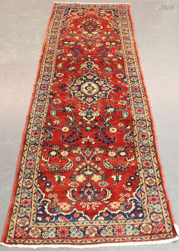 A Hamadan runner, North-west Persia, mid-20th century, the red field with a shaped medallion,