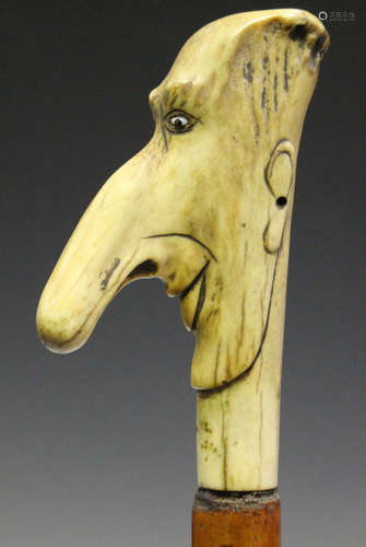 A Victorian Malacca shafted walking stick, the antler handle carved as the head of a long-nosed