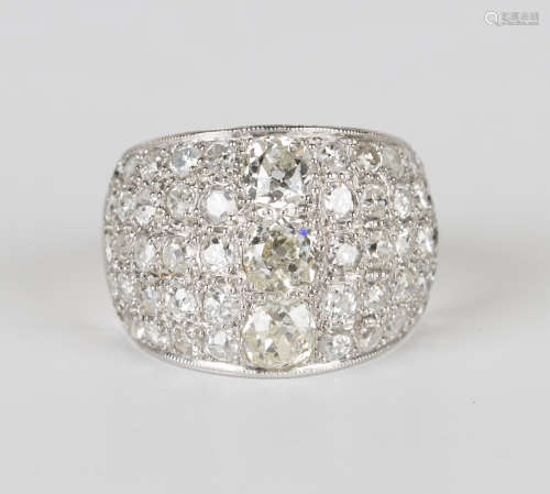 A white gold and diamond ring in a bombé design, mounted with a row of three principal circular