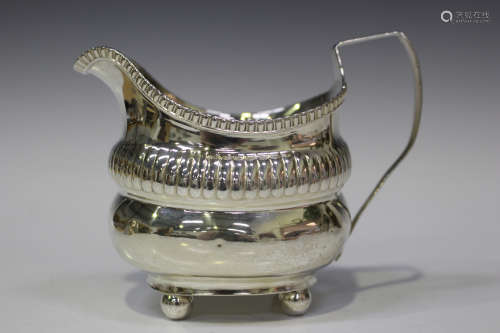 A George III silver milk jug, the waisted body with reeded rim, raised on ball feet, London 1813,