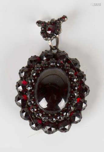 A Victorian Bohemian garnet oval pendant locket, the oval cabochon garnet within a two row