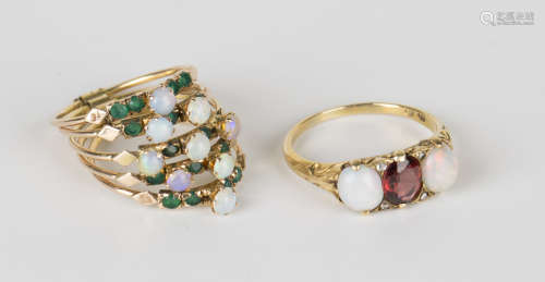 A gold ring, mounted with an oval cut garnet between two oval opals with two pairs of rose cut