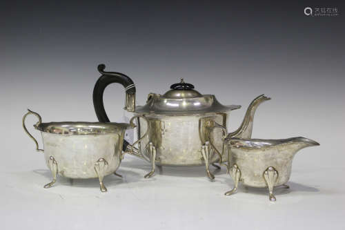 A George V silver three-piece tea set of oval form with shaped rims, raised on scroll legs,