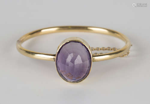 A gold and amethyst oval hinged bangle, the front mounted with an oval amethyst, on a snap clasp,